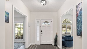 A hallway with a white door, a patterned rug, and a blue bench. - Peacock Paradise in Ocala (Ocala)