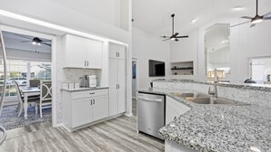 A modern kitchen with white cabinetry, granite countertops, and a dishwasher. - Peacock Paradise in Ocala (Ocala)
