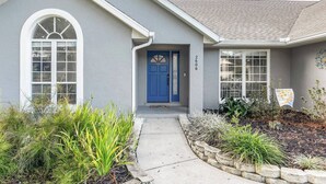 A residential house with a blue front door, a small porch, and a number '2606' on the wall. - Peacock Paradise in Ocala (Ocala)