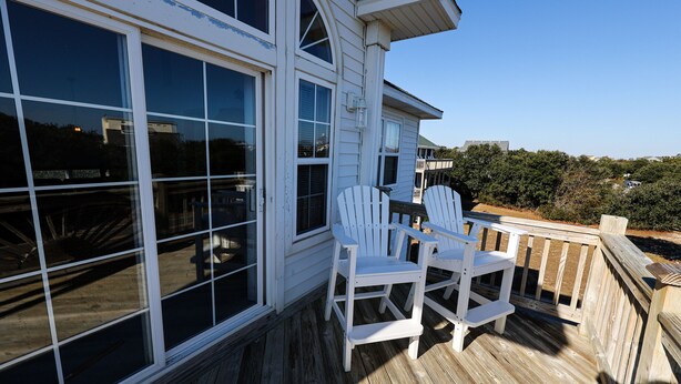 A wooden deck with two white Adirondack chairs and a table, overlooking a scenic landscape. - WH868- Beautiful 5 bedroom, 4.5 bath vacation rental house in Corolla! (Corolla)