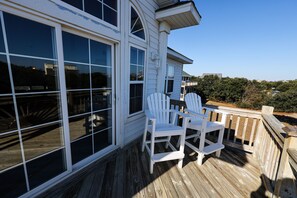 A wooden deck with two white Adirondack chairs and a table, overlooking a scenic landscape. - WH868- Beautiful 5 bedroom, 4.5 bath vacation rental house in Corolla! (Corolla)