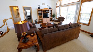 A living room with a brown sofa, wooden coffee table, and a television on a wooden stand. - WH868- Beautiful 5 bedroom, 4.5 bath vacation rental house in Corolla! (Corolla)