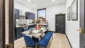 A modern kitchen with dark cabinets, a dining table set for four, and a large window.