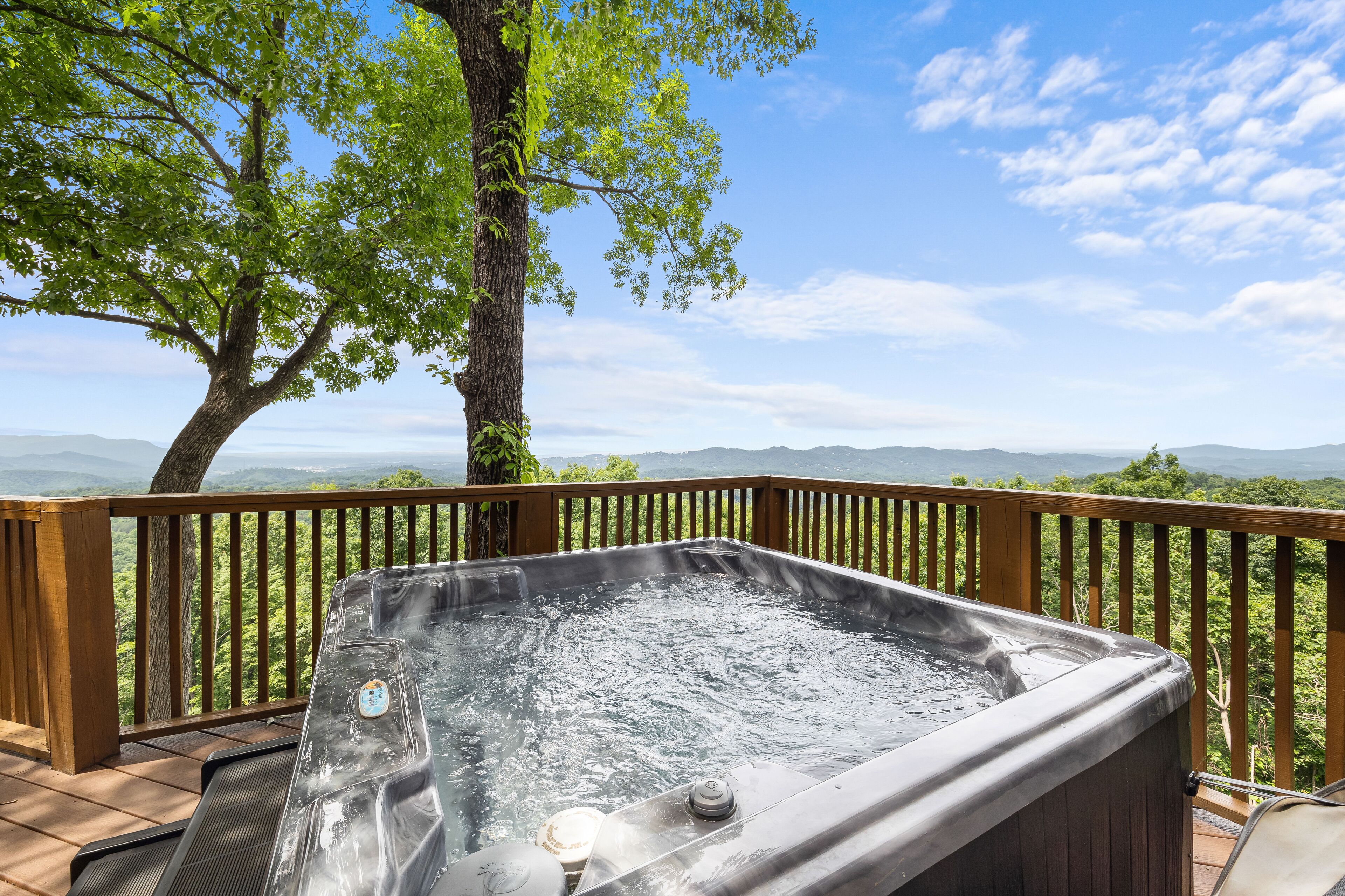 Ein Whirlpool auf einer Holzterrasse mit Blick auf eine schöne Berglandschaft.