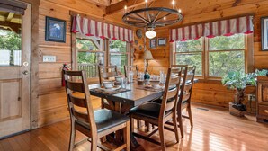 A wooden dining room with a large table, chairs, and a chandelier. - Resort*Panoramic Views*Gameroom*Gas Grill*Hot Tub*Wifi/Cable (GATLINBURG)