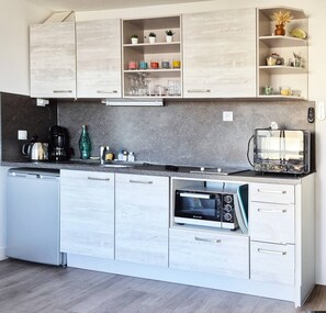 A modern kitchen with white cabinetry, a built-in oven, a coffee maker, and a toaster.