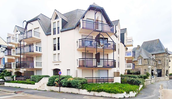 A multi-story residential building with balconies, a gated entrance, and a sign indicating a no parking zone. - Le belvédère de Port-lin - Les Gîtes de la Côte d'Amour (Le Croisic)