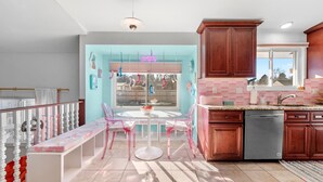 A kitchen with wooden cabinets, a dishwasher, and a window overlooking a backyard.