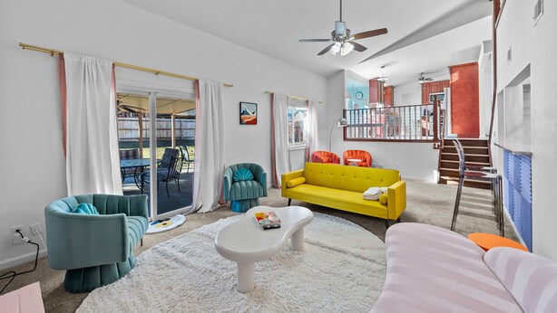 A modern living room with a white coffee table, a yellow sofa, and teal armchairs.
