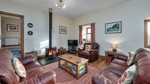Una sala de estar acogedora con sofás de cuero, una mesa de centro de madera, una chimenea y un televisor.