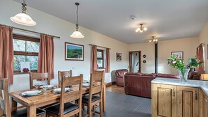 Un comedor con mesa y sillas de madera, una cocina con armarios de madera, y una sala de estar con sofá.
