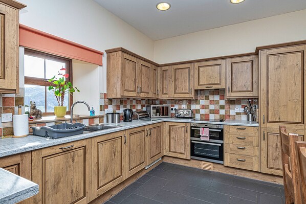 A kitchen with wooden cabinets, a sink, a window with a view, and a tiled backsplash.