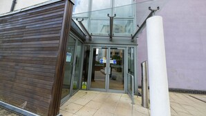 A building entrance with a glass door, a wooden shutter, and a sign indicating 'Alaska Building'.