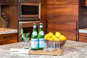 Una encimera de cocina con una botella de agua Pellegrino, un bol de limones y una tabla de cortar.
