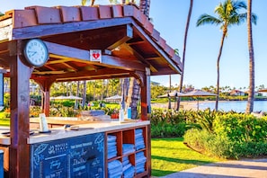 A wooden structure with a clock and an AED sign, a chalkboard with service provider information, and a view of a beach with palm trees.