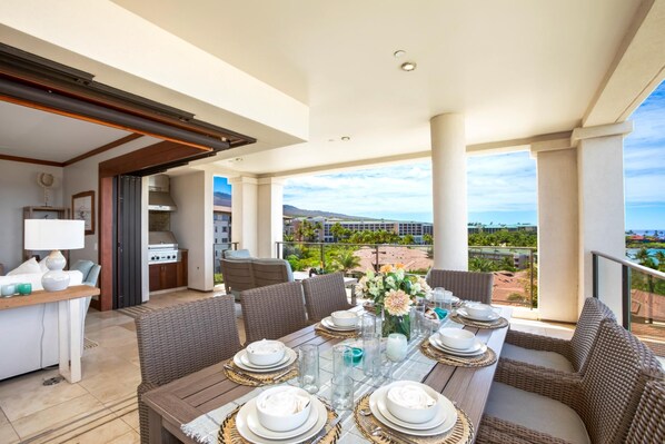 A dining area with a table set for six, a kitchen, and a view of a resort.