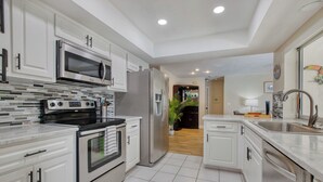 A modern kitchen with white cabinetry, stainless steel appliances, and a tiled floor. - VRCC Villa Paradise Palms (Cape Coral)