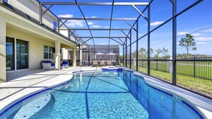Piscina com área coberta, água azul cristalina e vista para uma casa ao fundo.