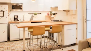 Una cocina moderna con una isla central, electrodomésticos de acero inoxidable, iluminación colgante y un suelo con diseño.