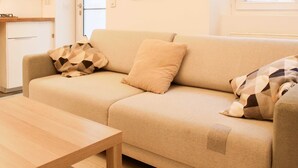 Una sala de estar con un sofá color beige, una mesa de centro de madera y un cuadro enmarcado en la pared.