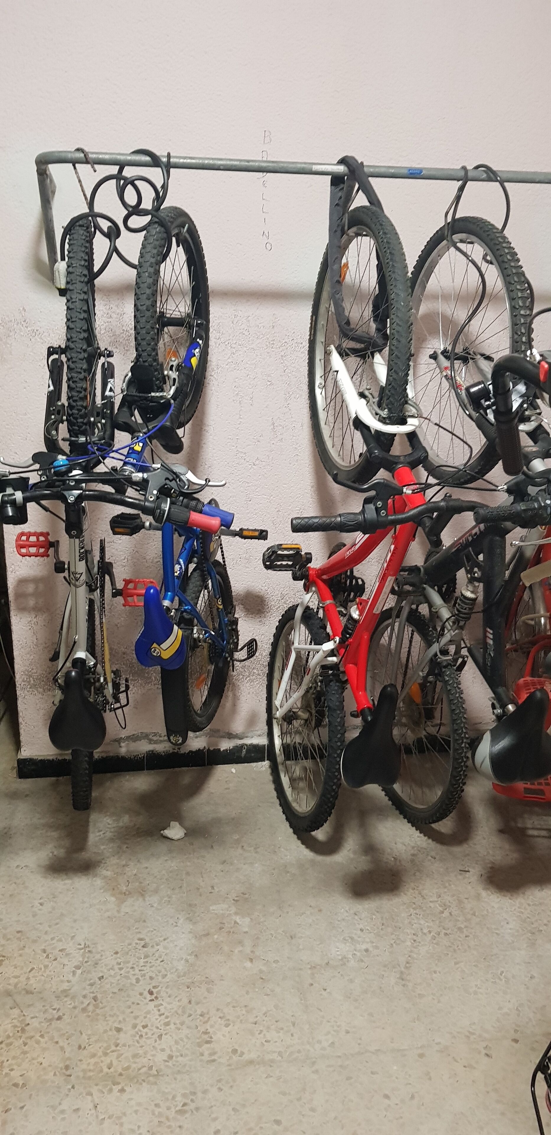 Un aparcaciclos con varias bicicletas y neumáticos junto a una pared.
