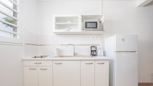 A modern kitchen with white cabinets, a built-in microwave, a coffee maker, and a refrigerator. - Studio 102 - Le Balisier (Les Trois-Îlets)