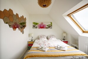 Un dormitorio con una cama, dos mesitas de noche, una ventana, una obra de arte en la pared y un candelabro en el techo.