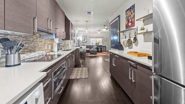 A modern kitchen with dark wood cabinets, stainless steel appliances, and a central island.