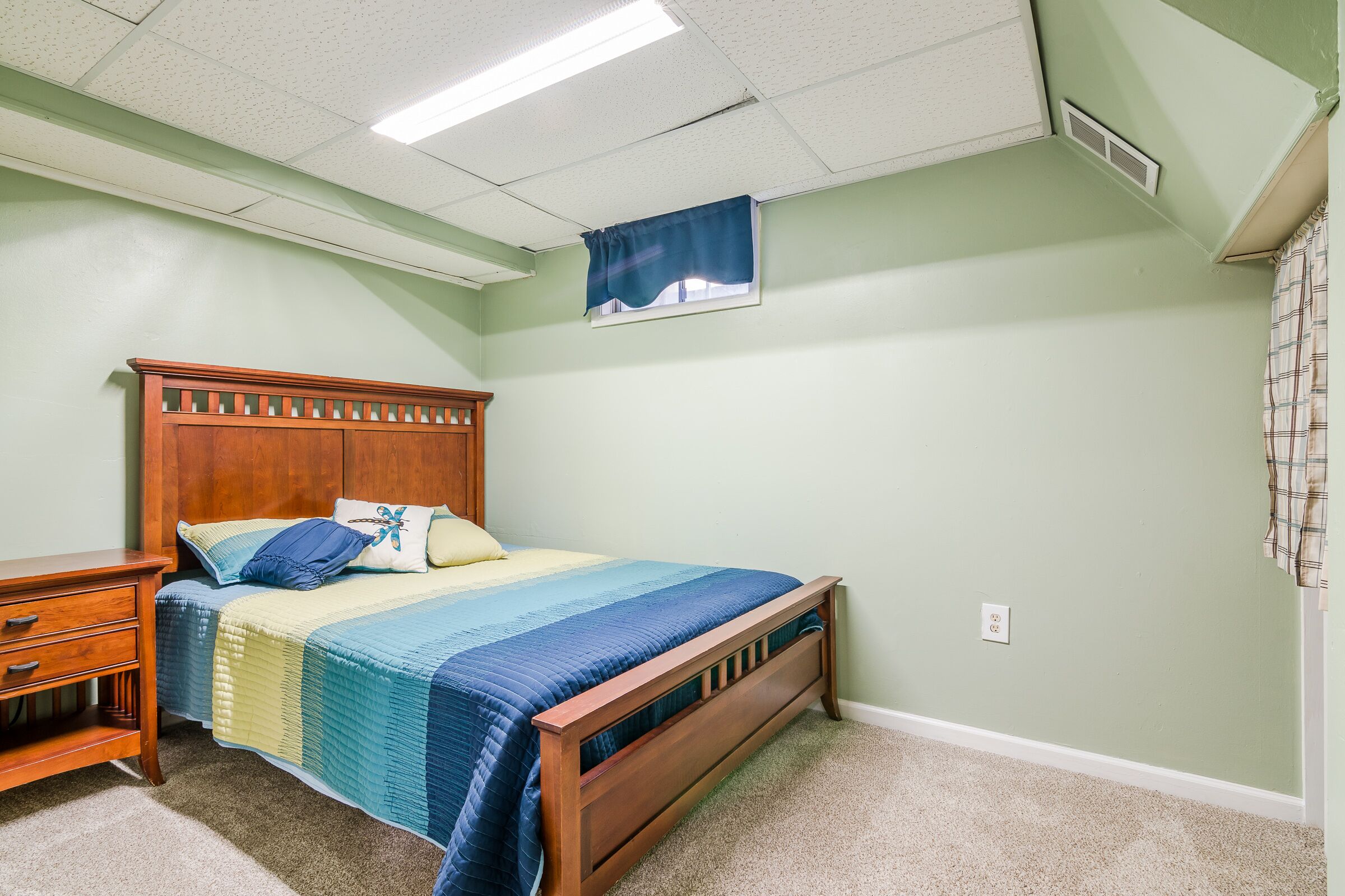 A bedroom with a wooden bed, a nightstand, and a wall-mounted shelf.