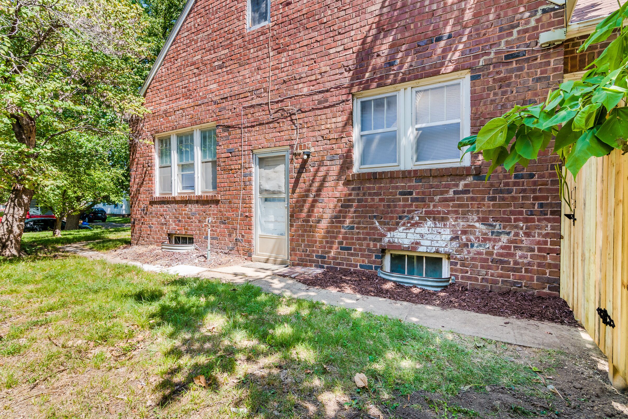 A brick building with a front door, windows, and a small window below the door.