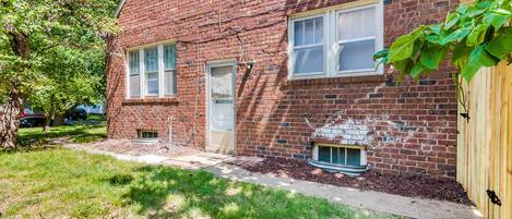 A brick building with a front door, windows, and a small window below the door.