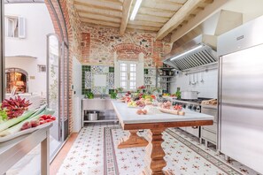 A kitchen with a large island, a brick wall, and a tiled backsplash.
