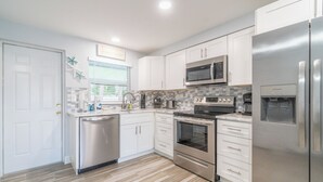 A modern kitchen with white cabinets, stainless steel appliances, and a tiled backsplash.