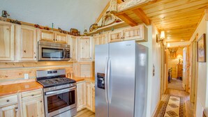 A wooden kitchen with a stainless steel refrigerator, oven, and microwave. - Roberts Home w/ Western Decor & Mountain Views! (Roberts)