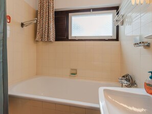 Bathroom features a bathtub, sink, and shower curtain with a floral pattern.