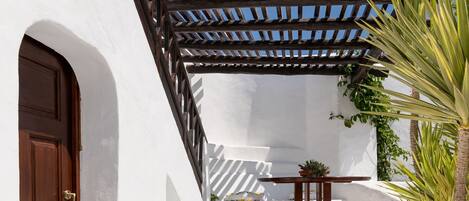 Ein weißes Gebäude mit einer Holztür und einer Pergola.