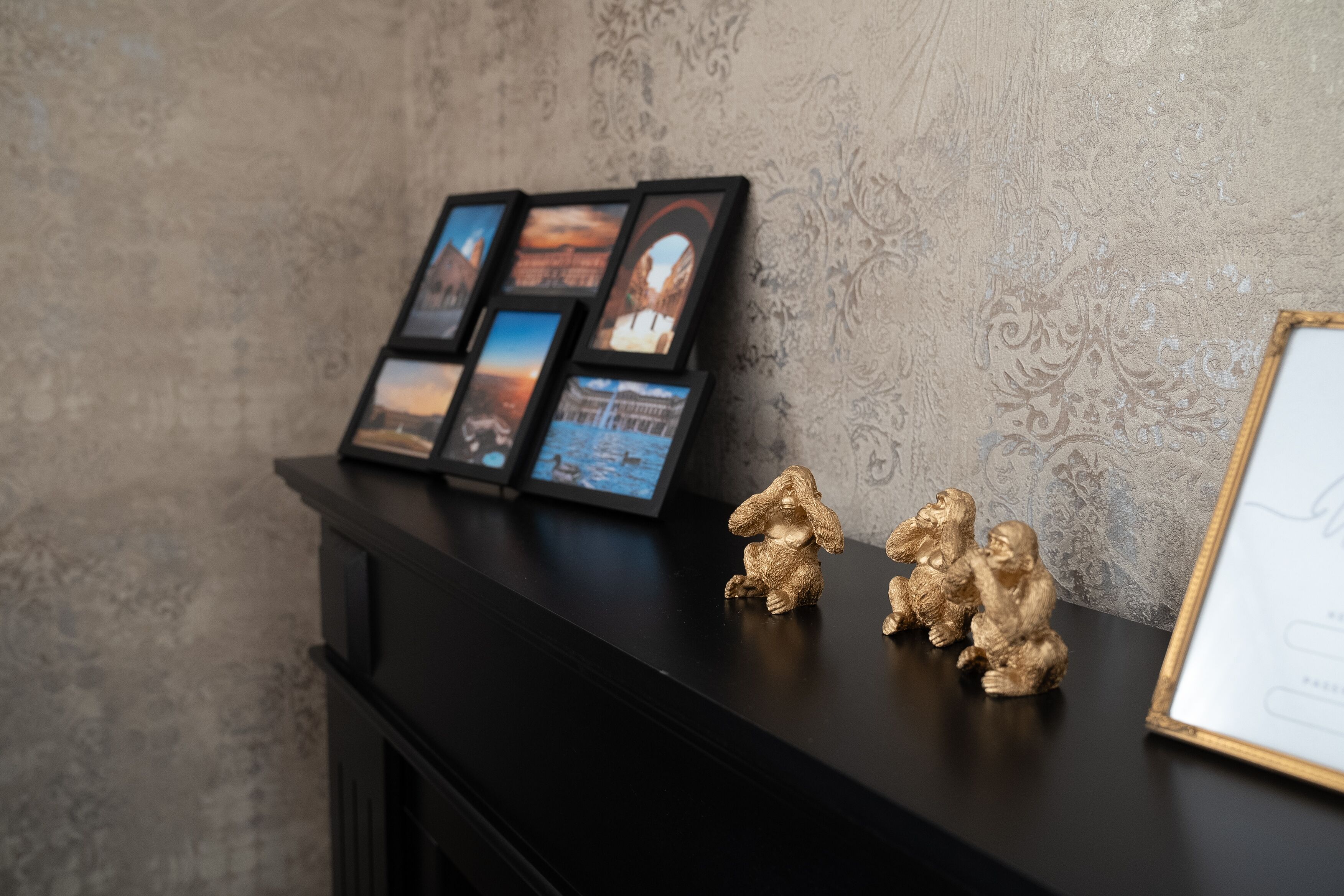 A black fireplace mantel with framed photographs and two small golden figurines.