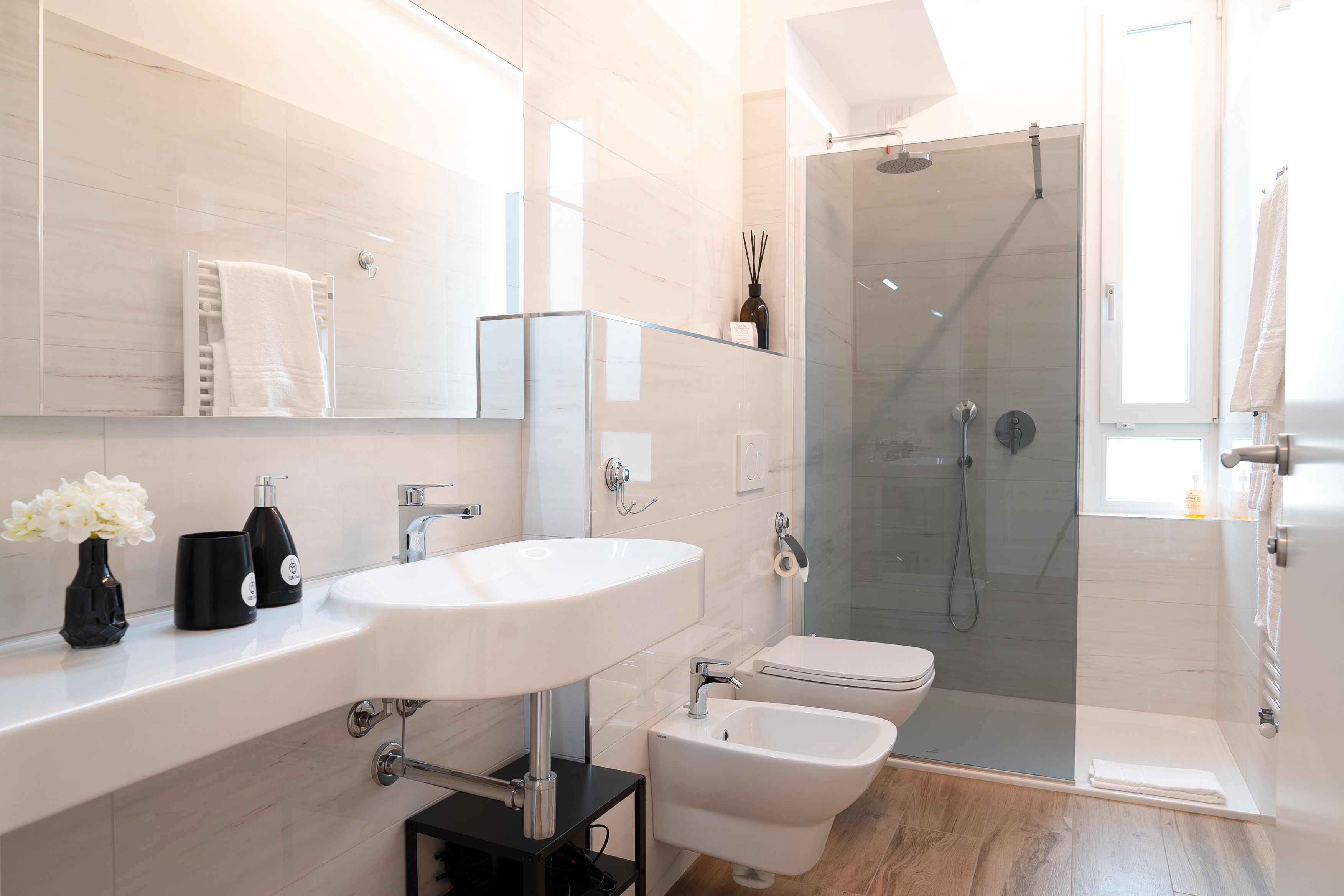 A modern bathroom with a large white sink, a glass-enclosed shower, and a toilet.