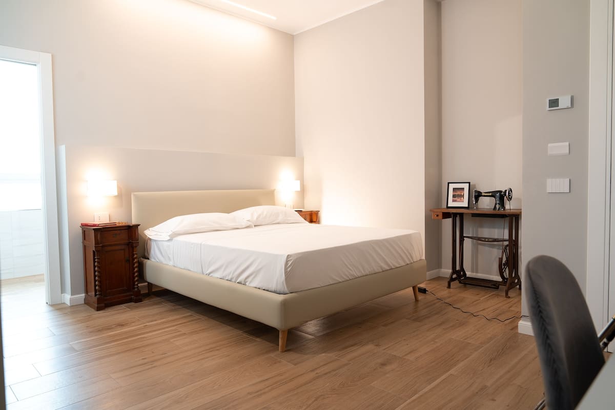 A bedroom with a bed, bedside tables, a desk, and a chair.
