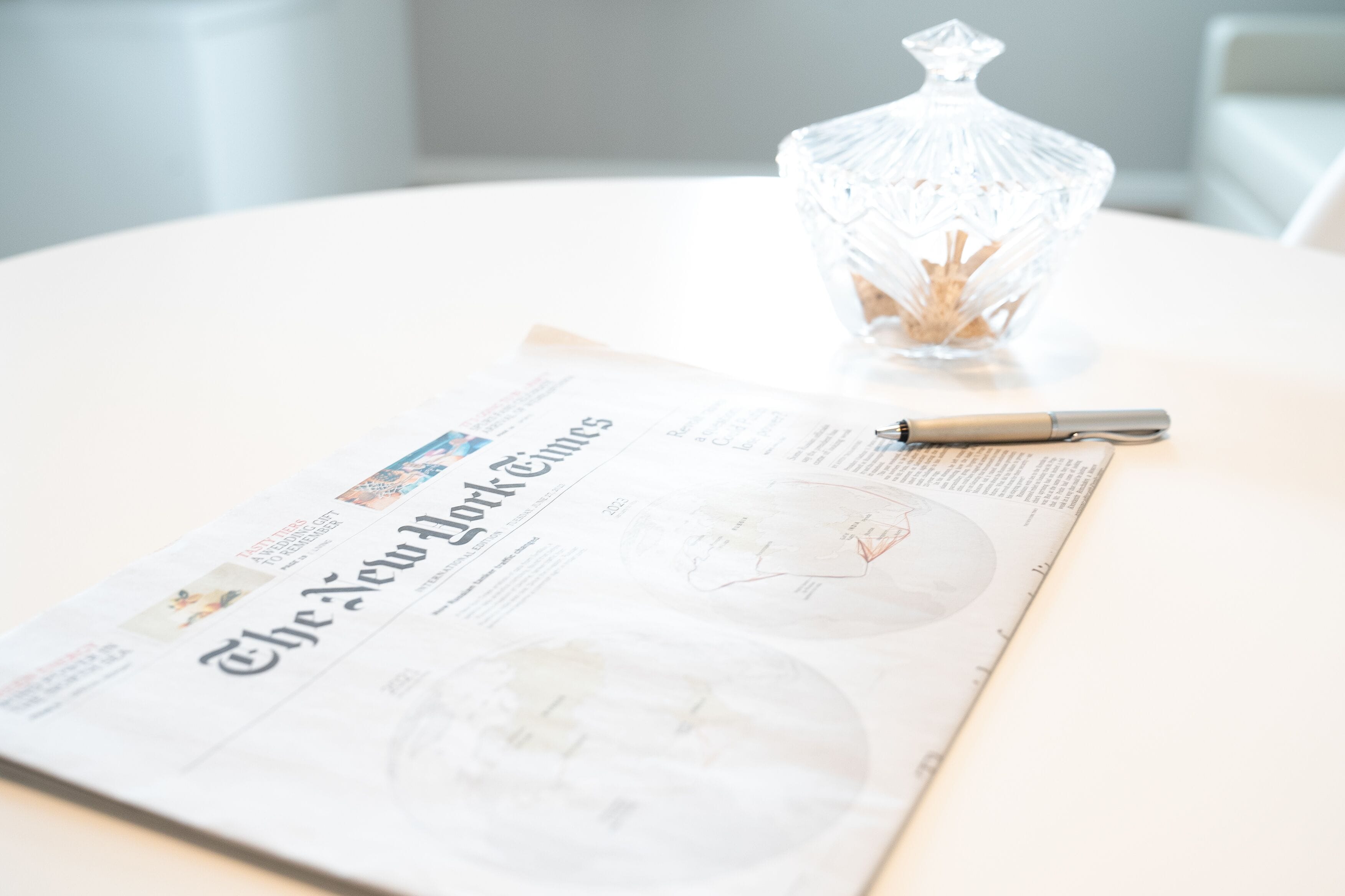 A clear view of a newspaper with the title "The New York Times" on a white table.