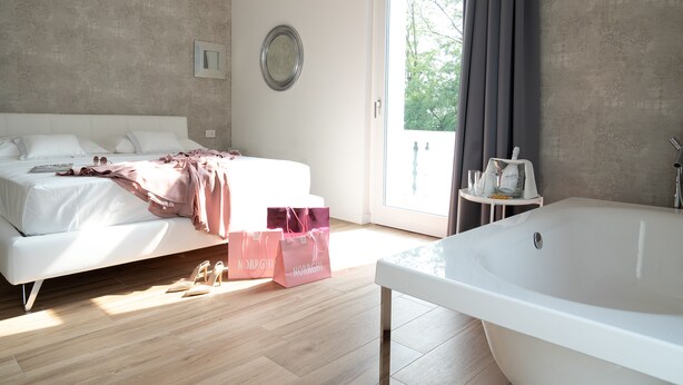 A bedroom with a bed, a large window, and a bathtub. - Villa Tosati (Monza)