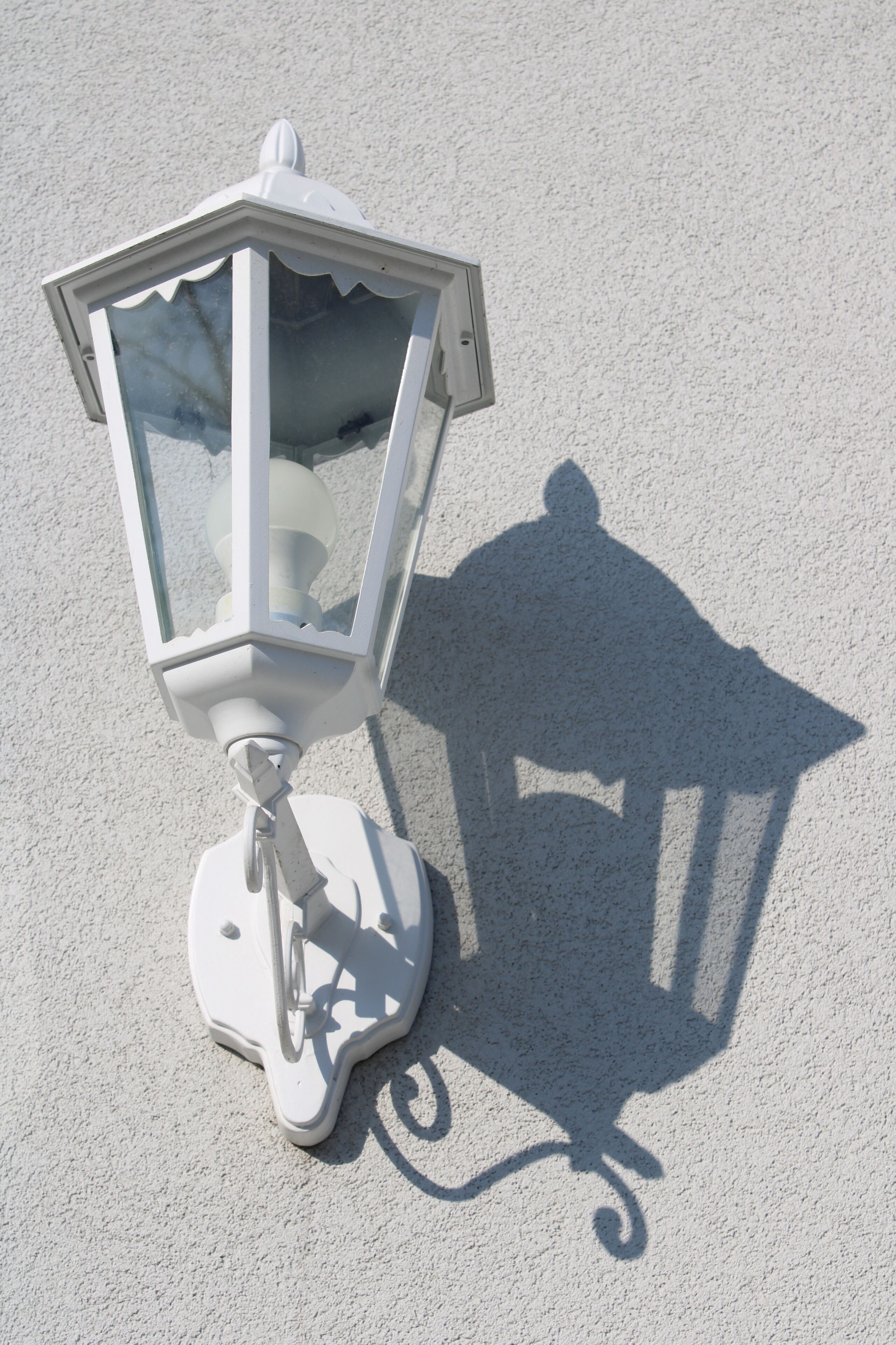 A white outdoor lantern on a textured surface.