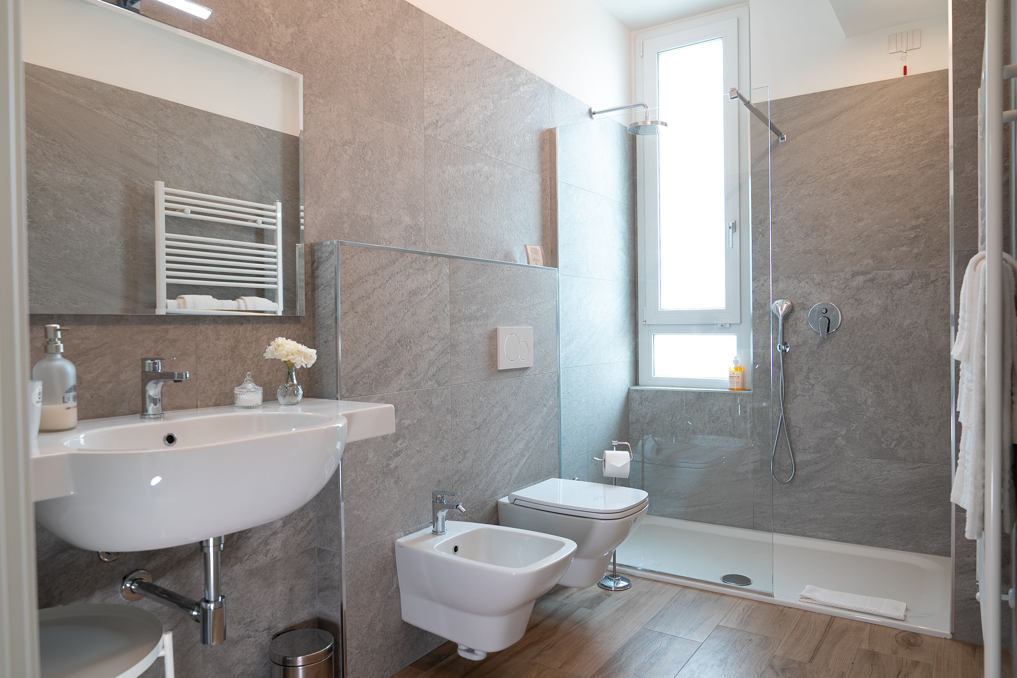 A modern bathroom with a sink, bidet, and glass-enclosed shower.