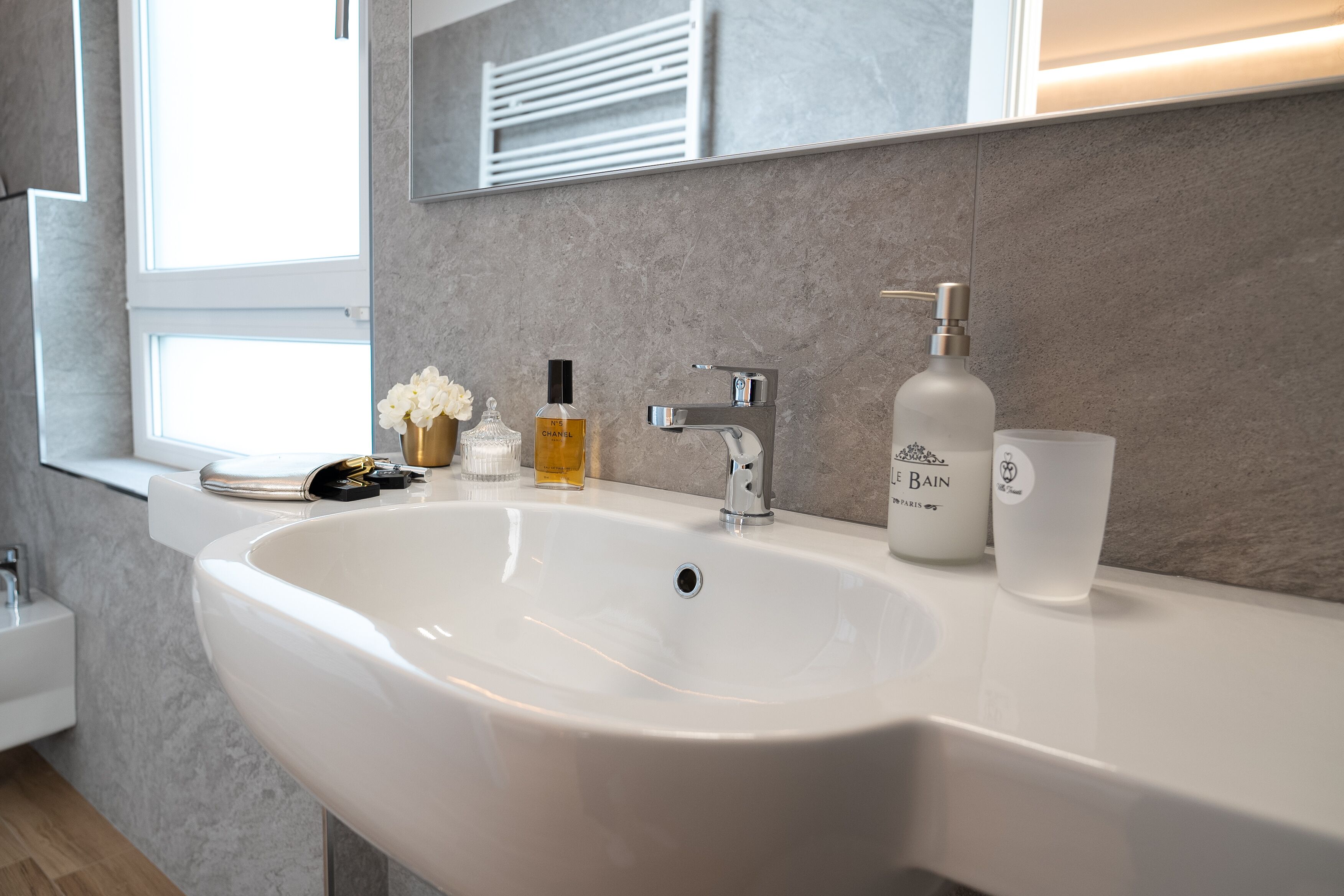 Une salle de bain moderne avec un grand lavabo blanc, un miroir et une fenêtre.