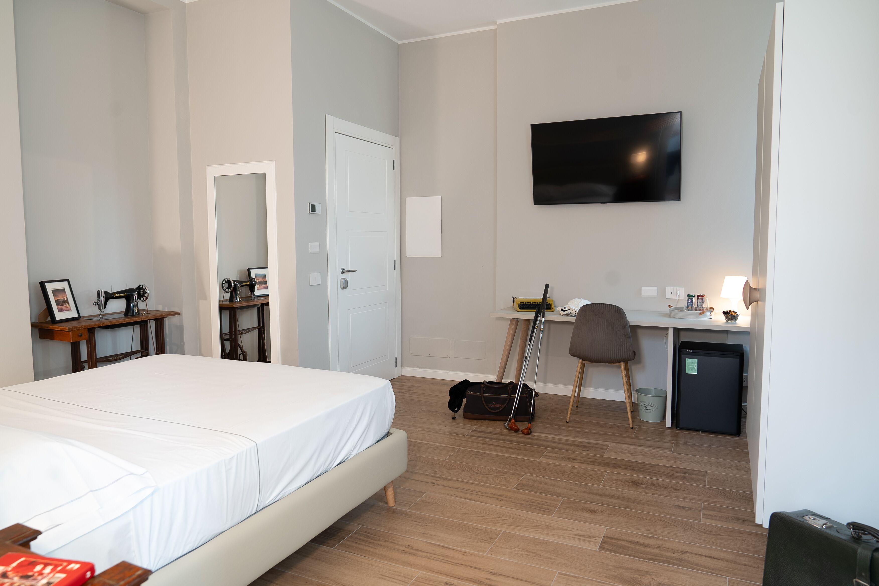 Een hotelkamer met een bed, bureau, stoel, televisie en een kleine koelkast.