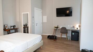 Een hotelkamer met een bed, bureau, stoel, televisie en een kleine koelkast.