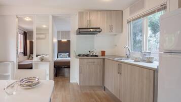 A modern kitchen with wooden cabinets, a gas stove, and a window providing natural light.