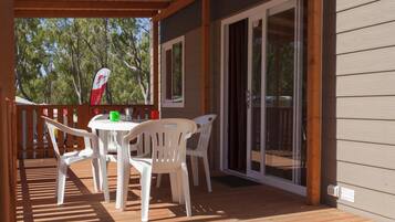 A covered outdoor area with a table and chairs, a flag, and a sliding glass door.