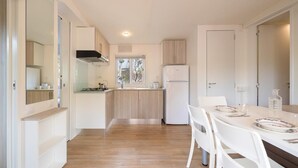 A modern kitchen with white cabinets, a wooden countertop, and a dining area with a white table and chairs.