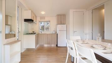 A modern kitchen with white cabinets, a wooden countertop, and a dining area with a white table and chairs.